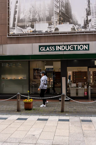 Technician repairing a storefront glass door with specialized equipment on a busy NYC street.