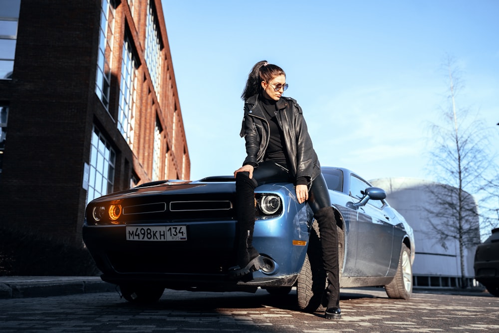 a woman leaning on the hood of a car