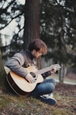 a man sitting on the ground playing a guitar