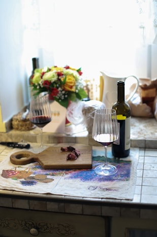 A cozy kitchen scene with a bottle of red wine and two glasses ready for pouring.