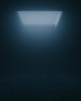 A dark, shadowy room with a single rectangular opening at the top that emits soft light. The space is dimly illuminated, and a pair of glowing eyes appear at the center of the image, belonging to a mysterious, unidentifiable figure.