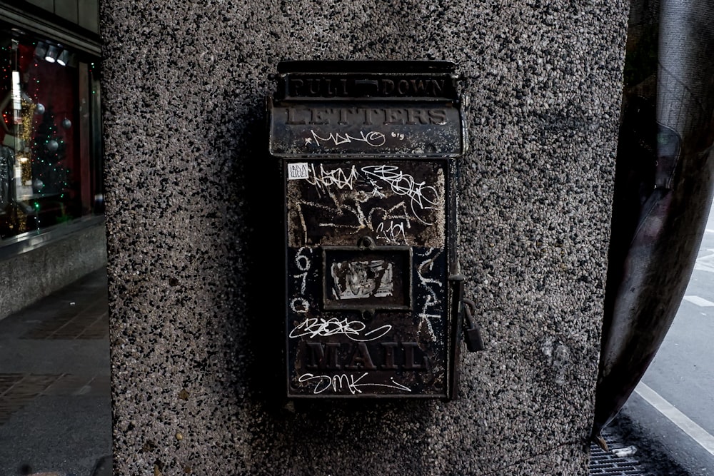 a mailbox covered in graffiti on the side of a building