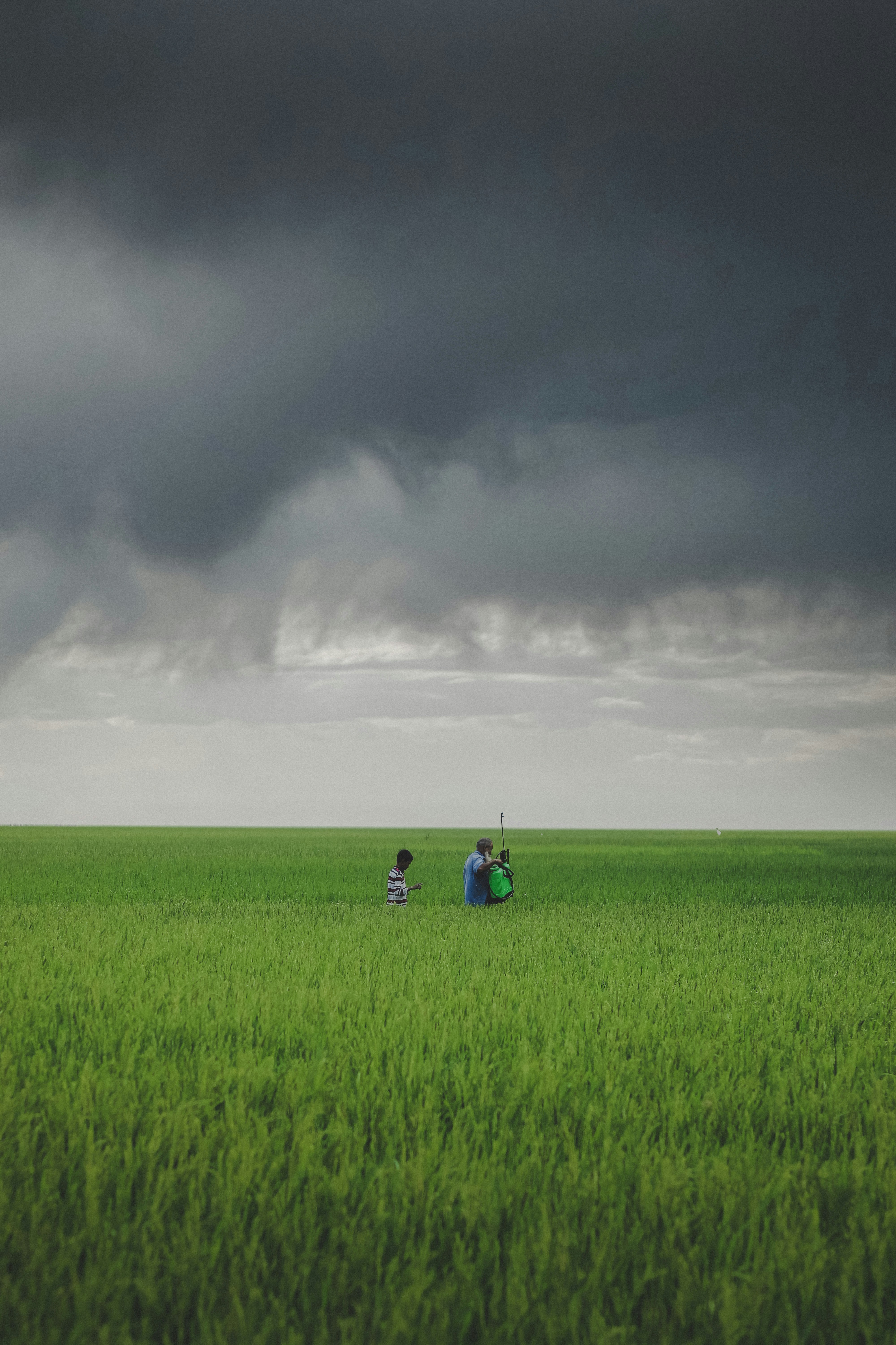 Un par de personas de pie en un campo bajo un cielo nublado