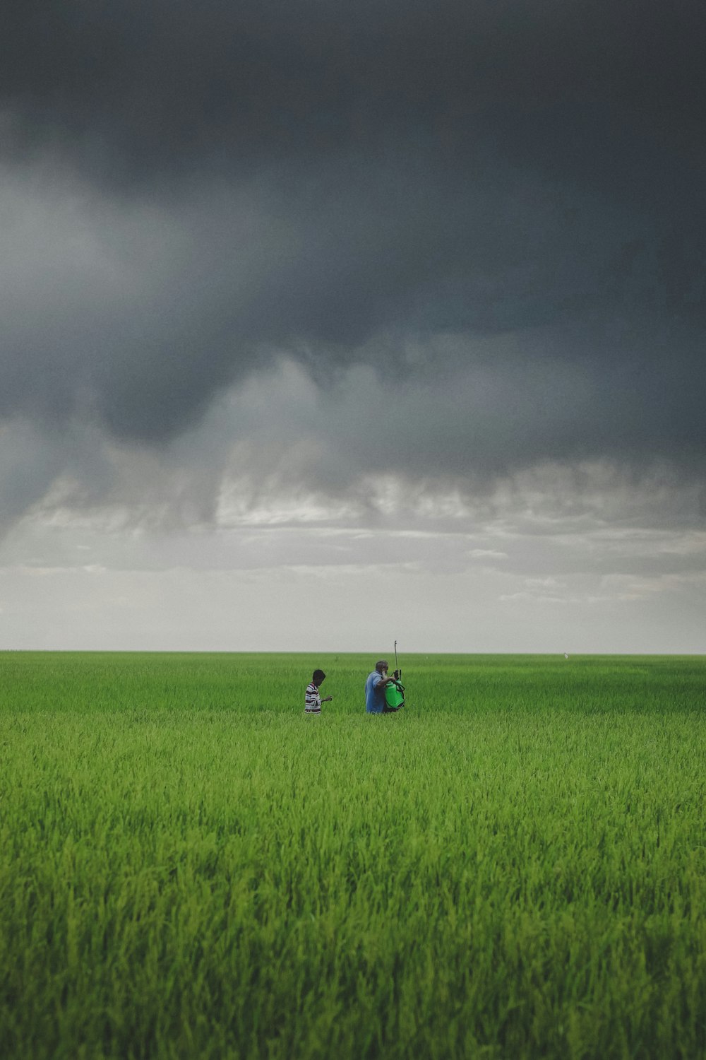 a couple of people standing in a field under a cloudy sky