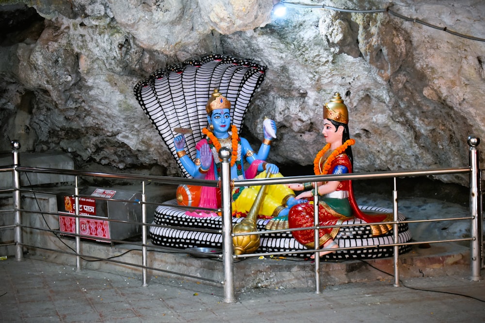 a couple of statues sitting on top of a metal bench