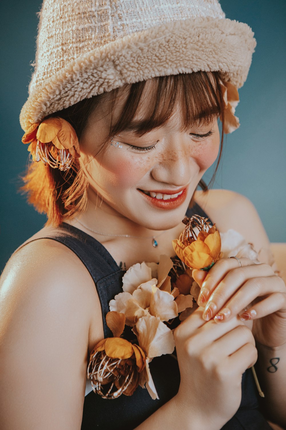 a woman wearing a hat and holding flowers