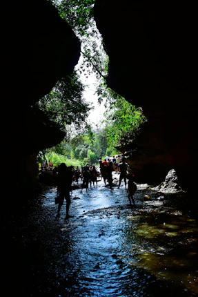 A guide leading a small group through a narrow, rocky canyon with clear water pools in Innsbruck.