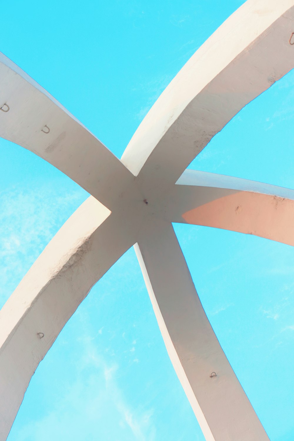 the underside of a white sculpture against a blue sky