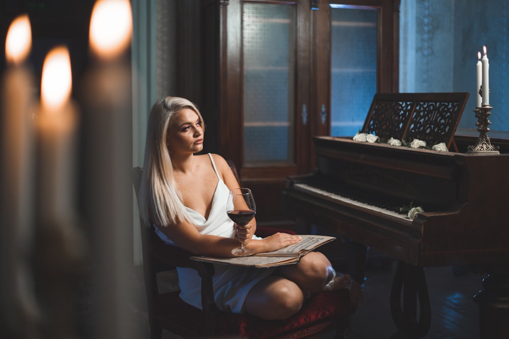 a woman sitting at a piano with a glass of wine