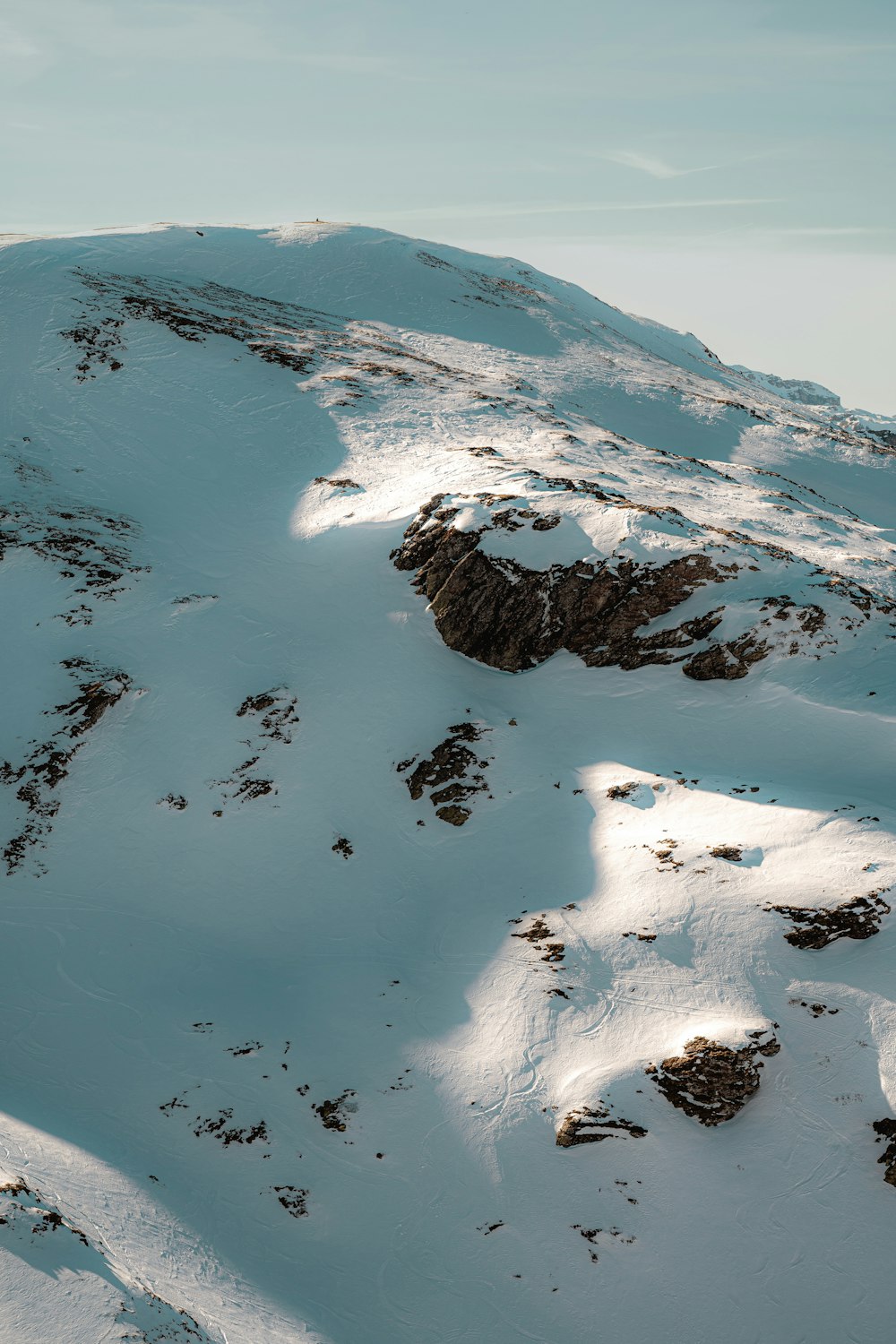 a mountain covered in snow with a sky background