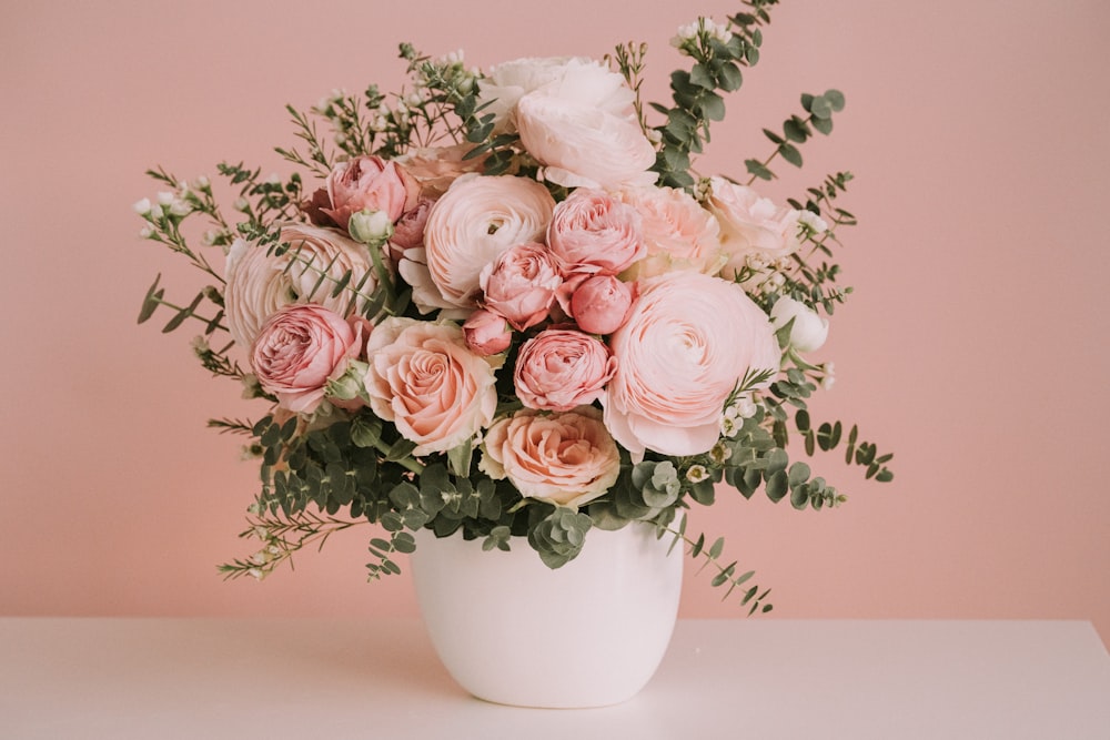 a white vase filled with lots of pink flowers