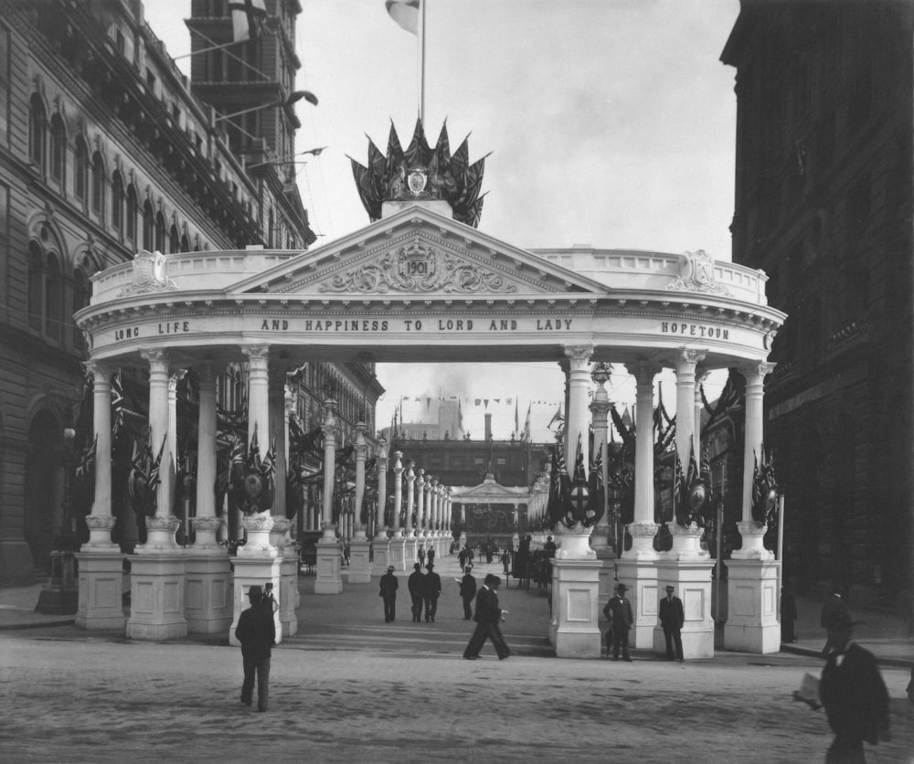 a black and white photo of people walking around a building