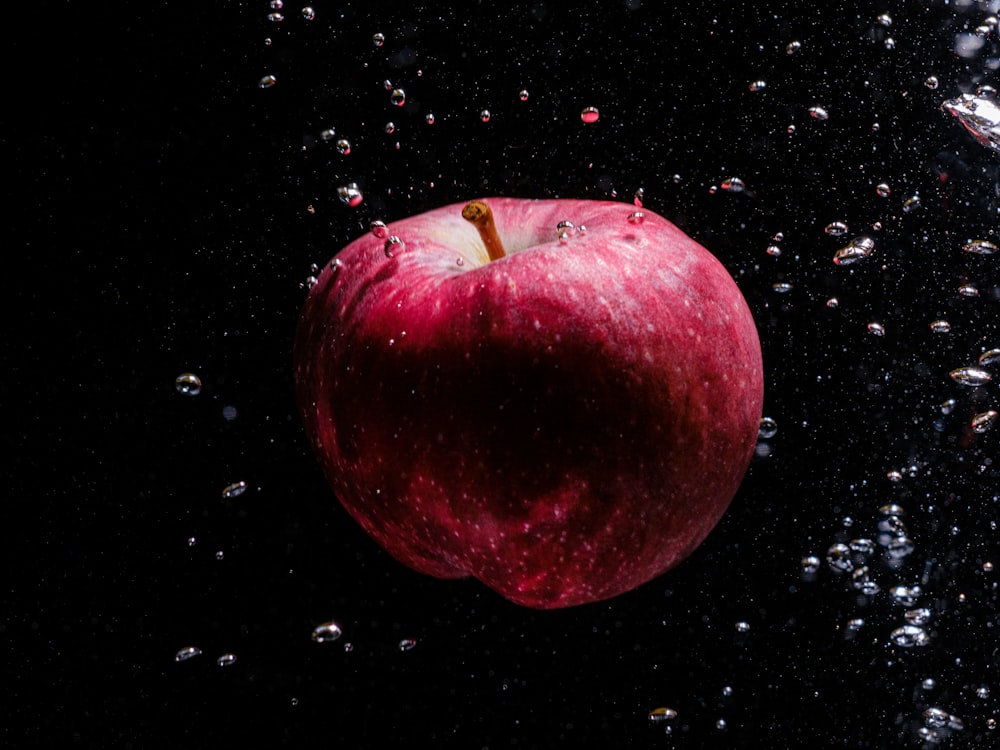 a red apple floating in water with bubbles