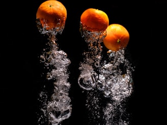 three oranges are splashing into the water