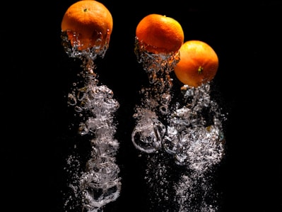 three oranges are splashing into the water