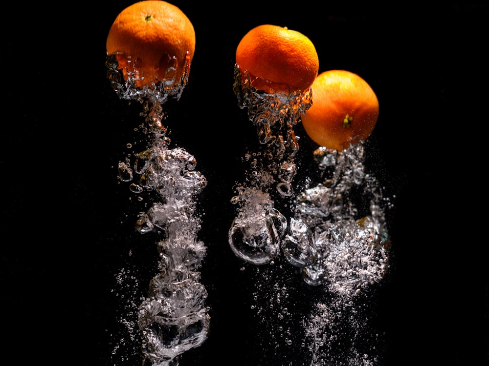 three oranges are splashing into the water