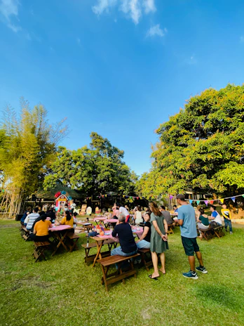 A vibrant group activity with smiling clients and support staff enjoying an outdoor picnic under colorful decorations.