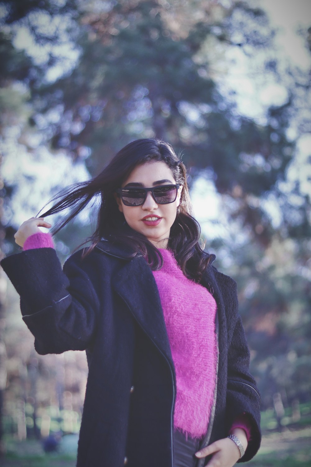 a woman wearing sunglasses and a pink sweater