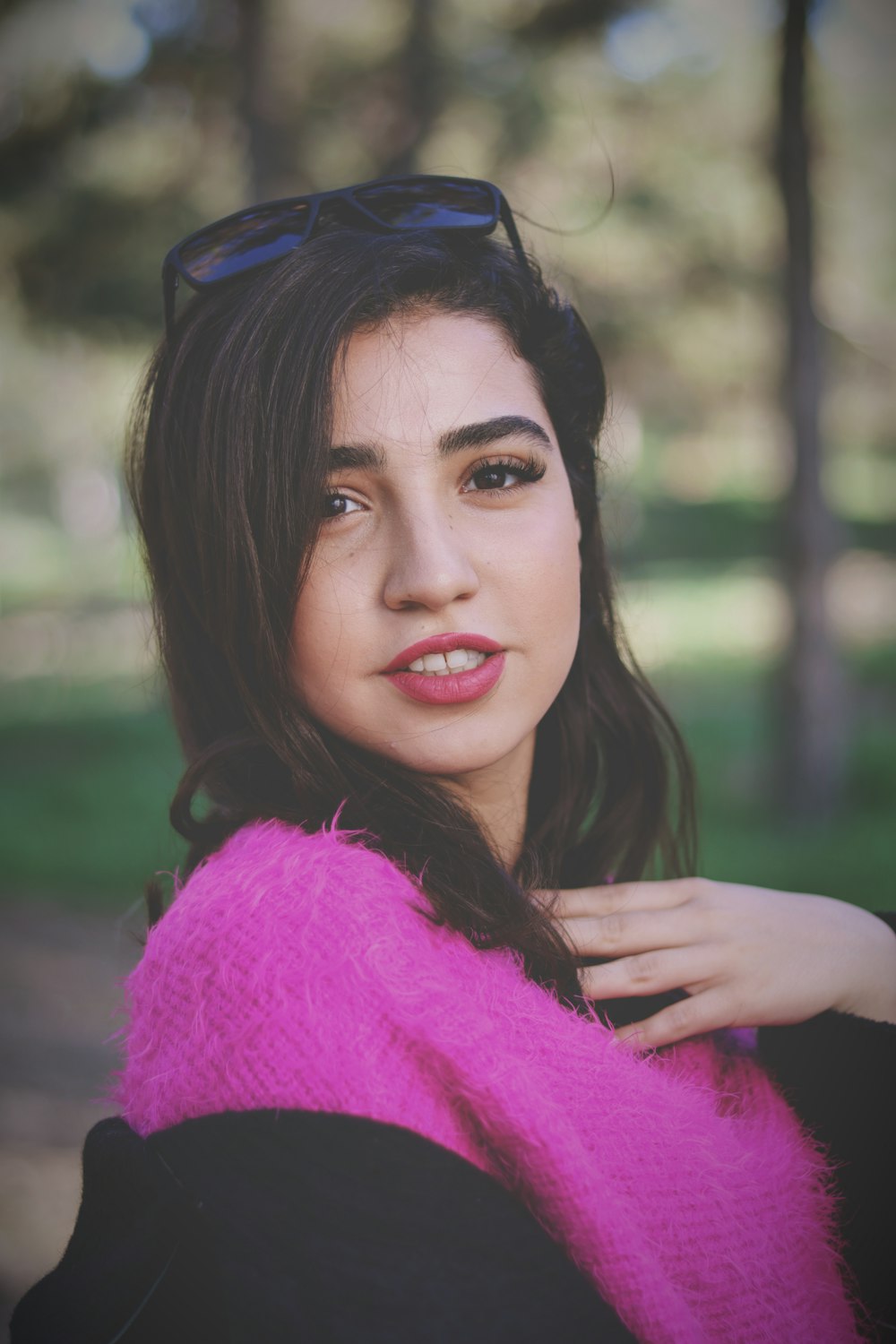 a woman wearing sunglasses and a pink scarf