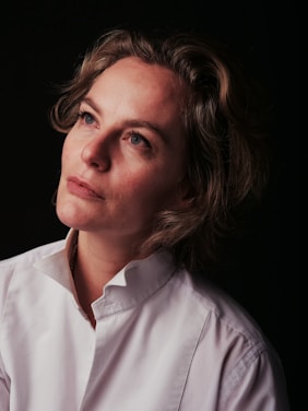 a woman in a white shirt looking off into the distance
