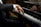 A person dressed in a black suit is playing a grand piano, focusing on the hands and keys. The sleeve has three buttons. The piano is a Steinway & Sons model with a shiny black surface reflecting the player’s hands.