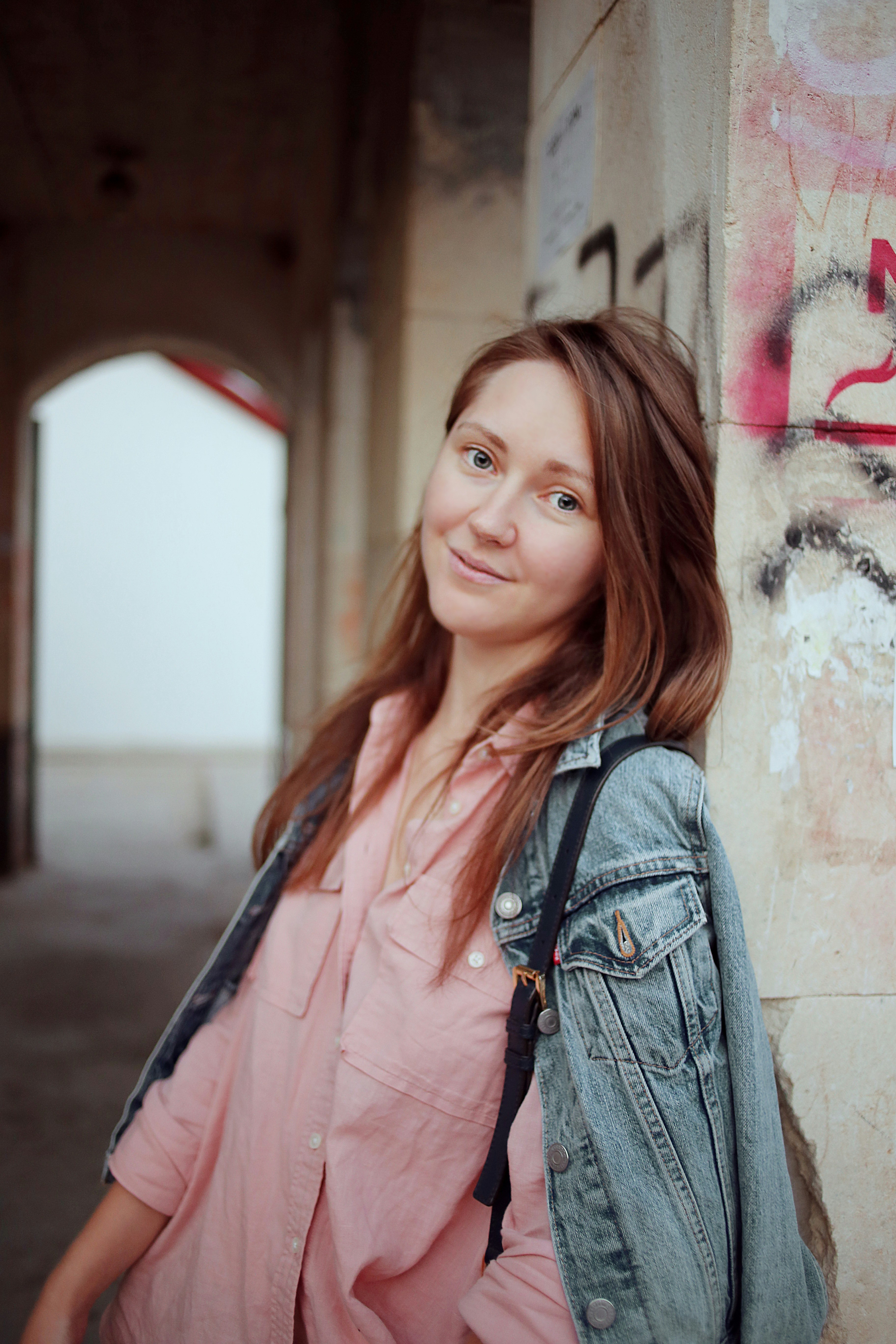 a woman standing next to a wall with graffiti on it