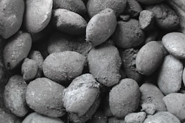 Stacks of premium charcoal briquettes ready for export with a charcoal grey background.