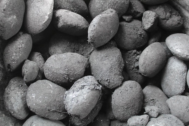 Close-up of dark, uniform coconut charcoal briquettes stacked neatly on a wooden pallet.