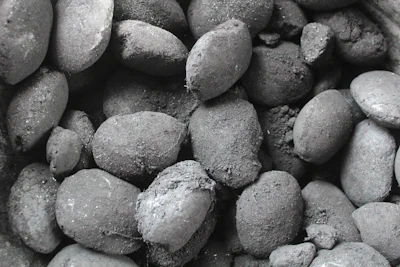 Close-up of sleek charcoal briquettes neatly arranged inside a custom-designed black inner box with gold accents.