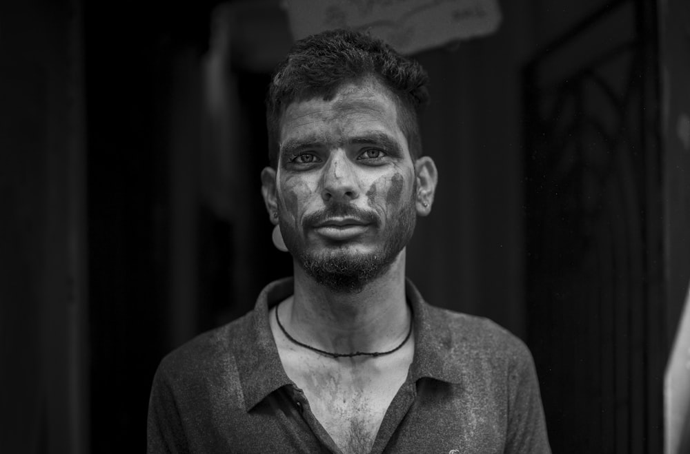 a black and white photo of a man with mud on his face