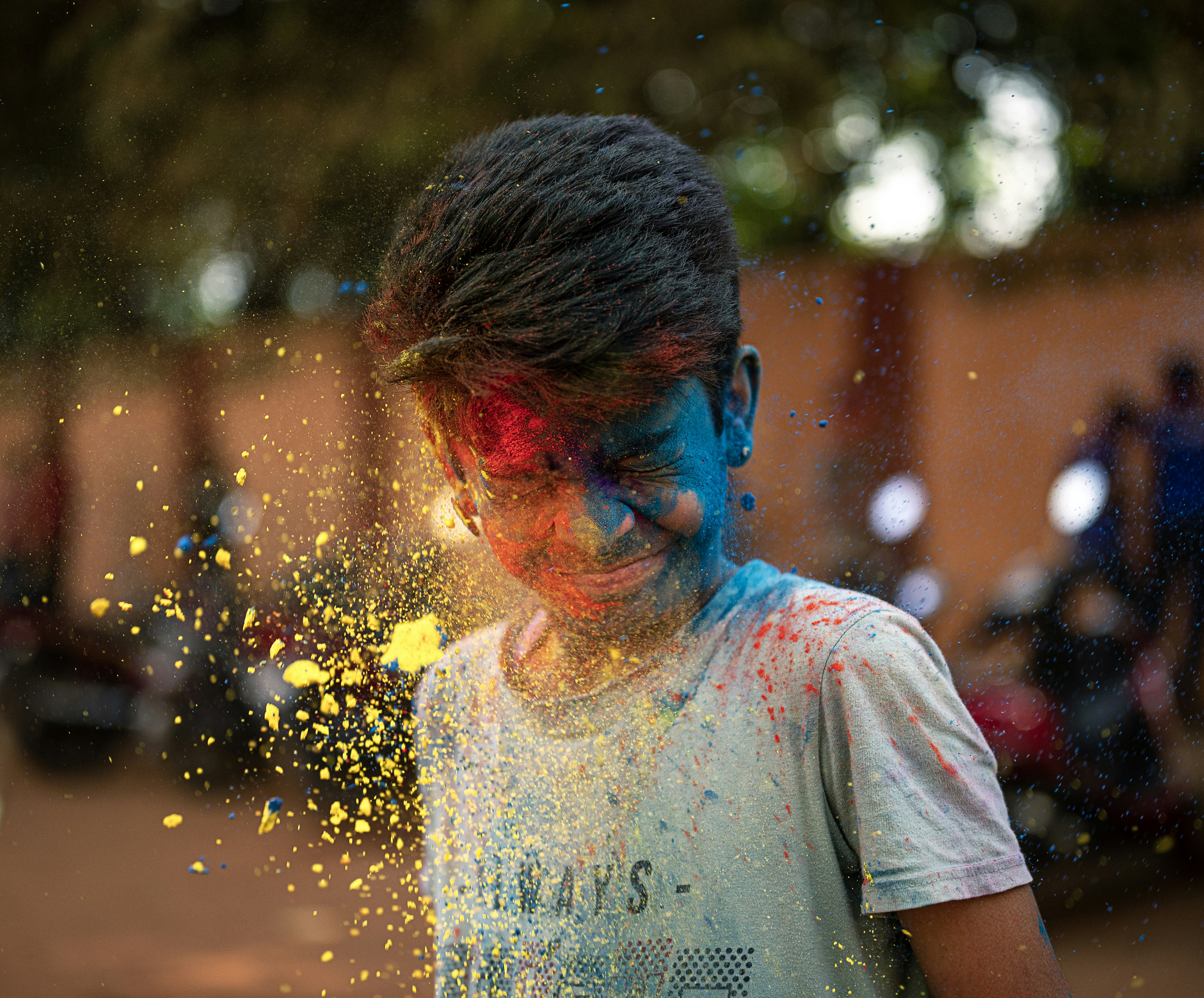 a young boy covered in yellow and blue powder
