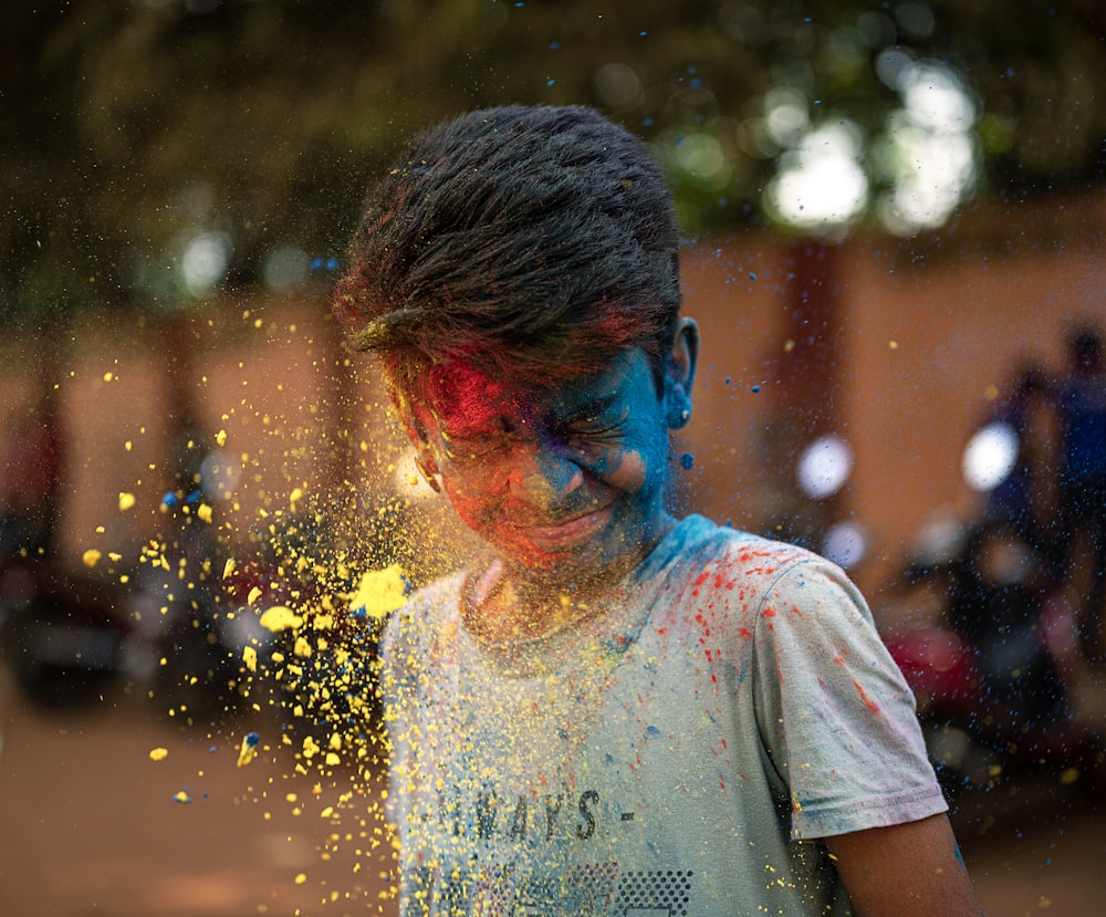 a young boy covered in yellow and blue powder