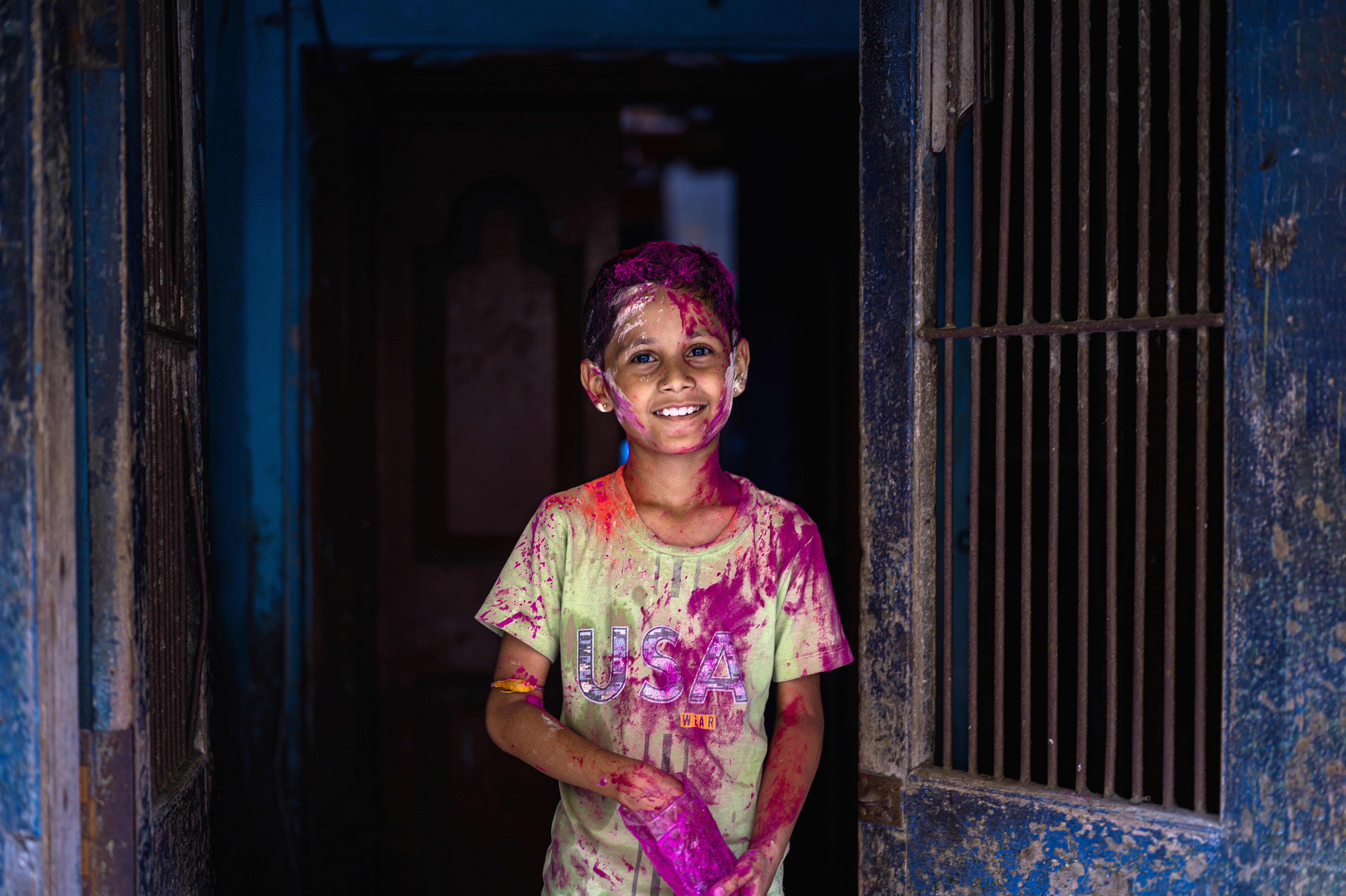 a young boy is standing in a doorway with colored paint on his face