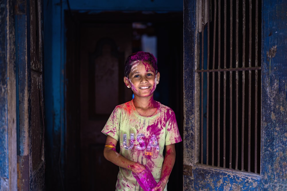 a young boy is standing in a doorway with colored paint on his face