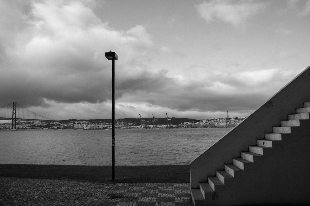 a black and white photo of a staircase next to a body of water