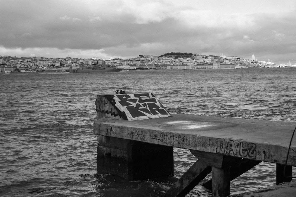 a black and white photo of a pier with graffiti on it