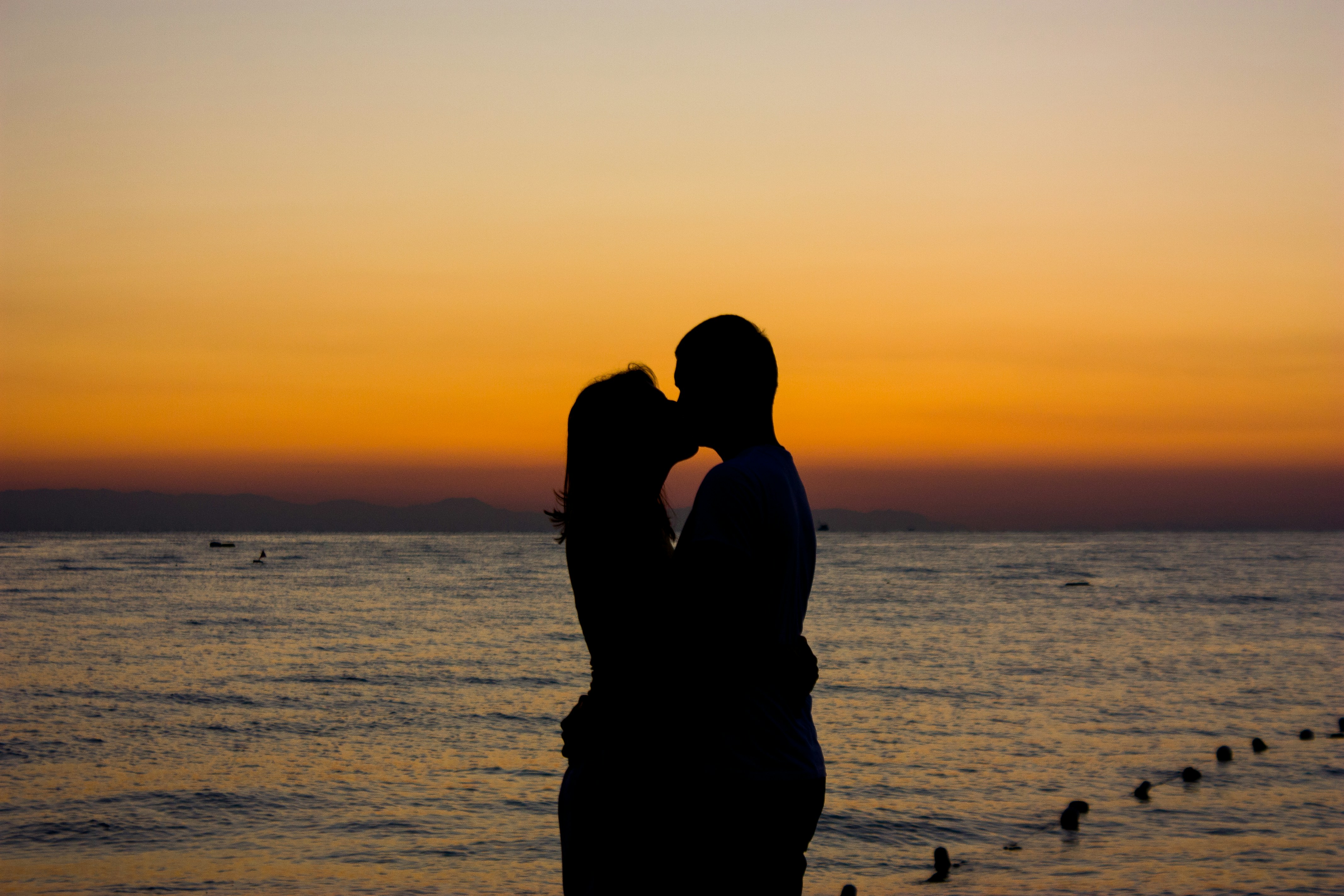 A man and a woman kissing in front of a body of water