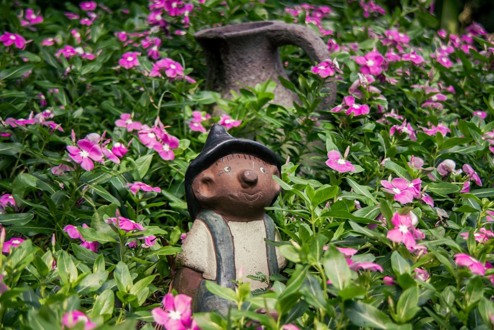 a small figurine in the middle of a field of flowers