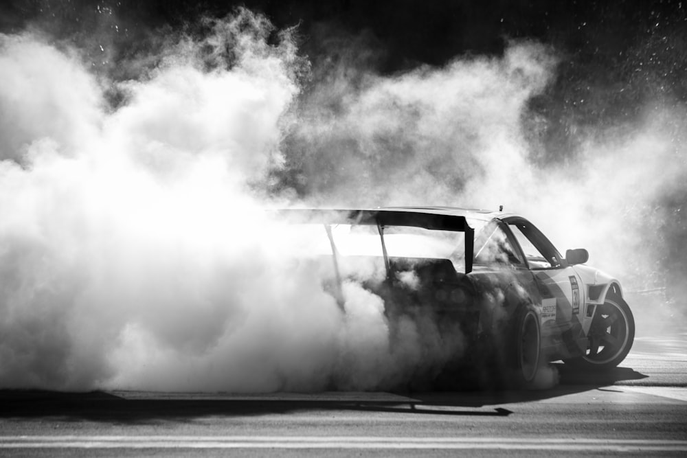 a black and white photo of a car with smoke coming out of it