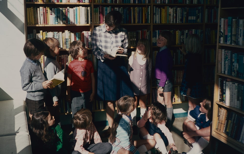 a group of children standing in front of a bookshelf
