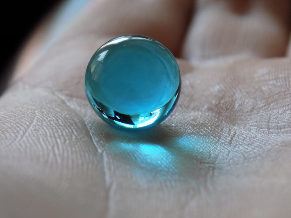 a close up of a person's hand holding a glass ball