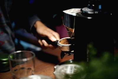 Hands pouring freshly ground coffee into a vintage coffee maker on a cozy kitchen counter.