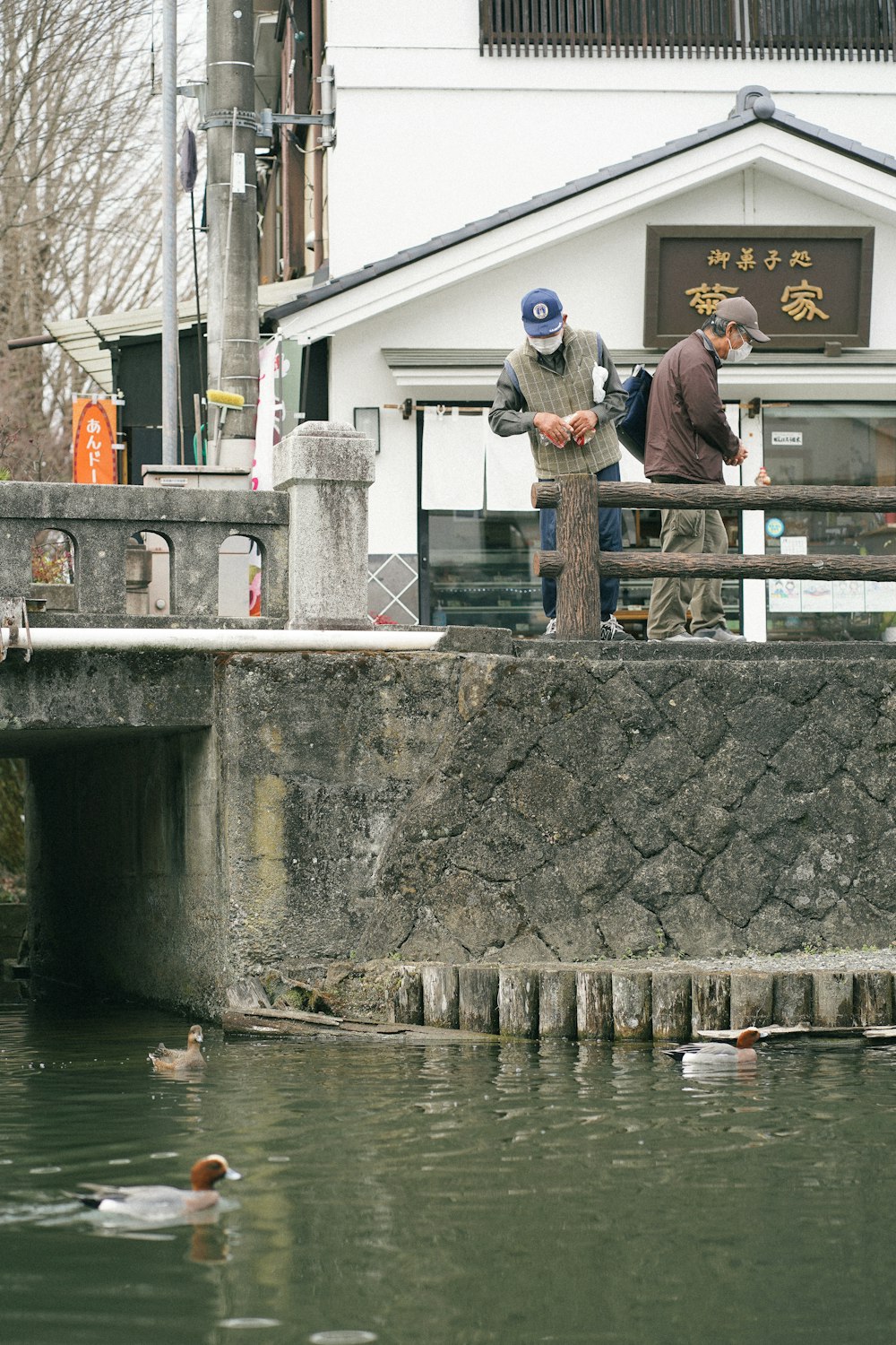 a couple of men standing on a bridge over a body of water