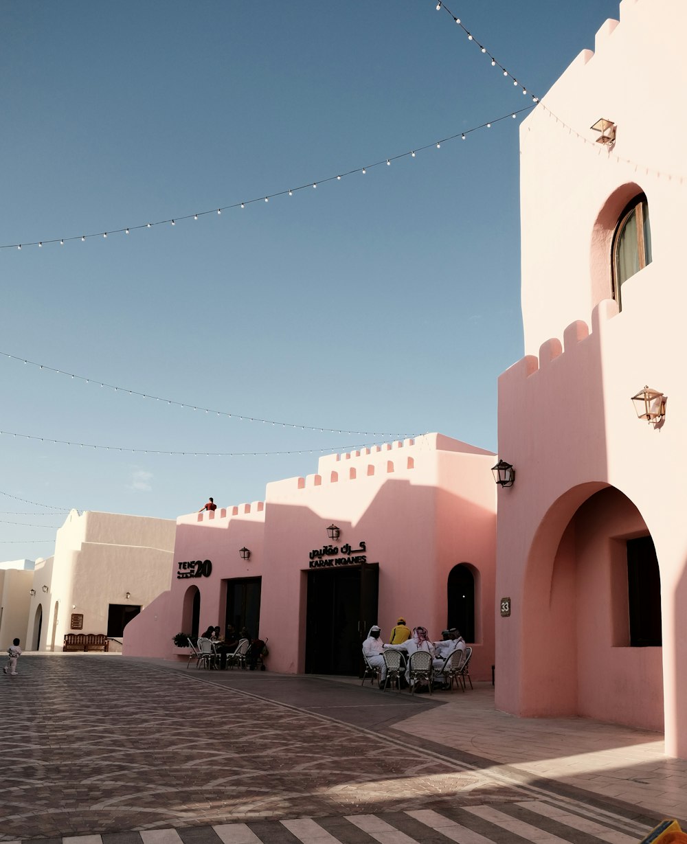 a couple of people sitting at a table in front of a pink building