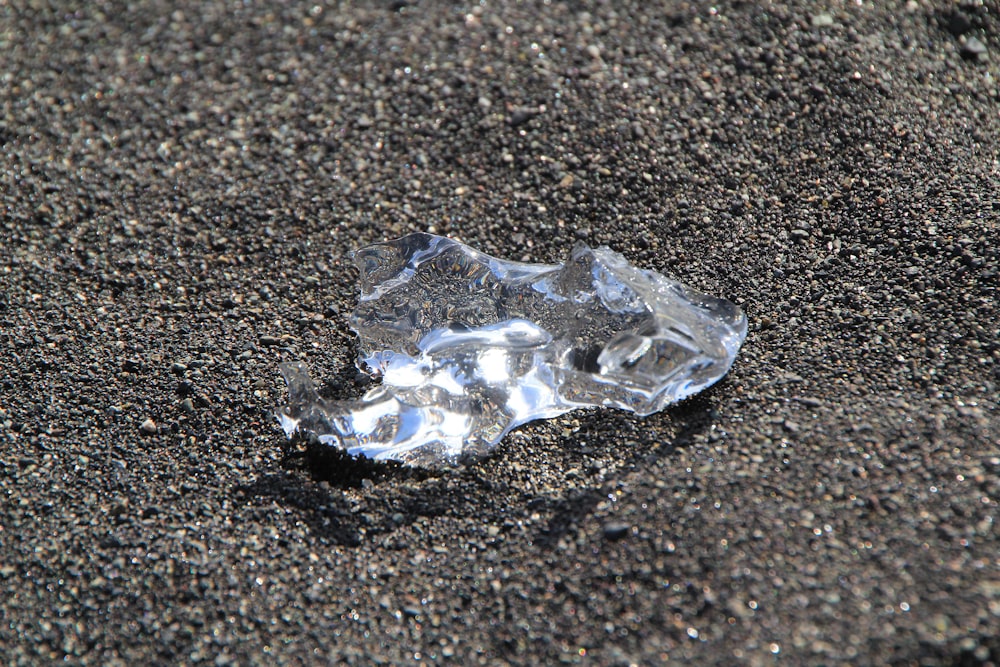 a piece of ice sitting on top of a sandy beach