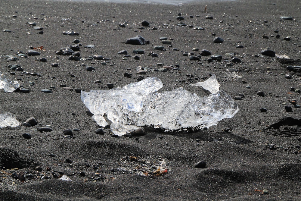 a piece of ice sitting on top of a sandy beach