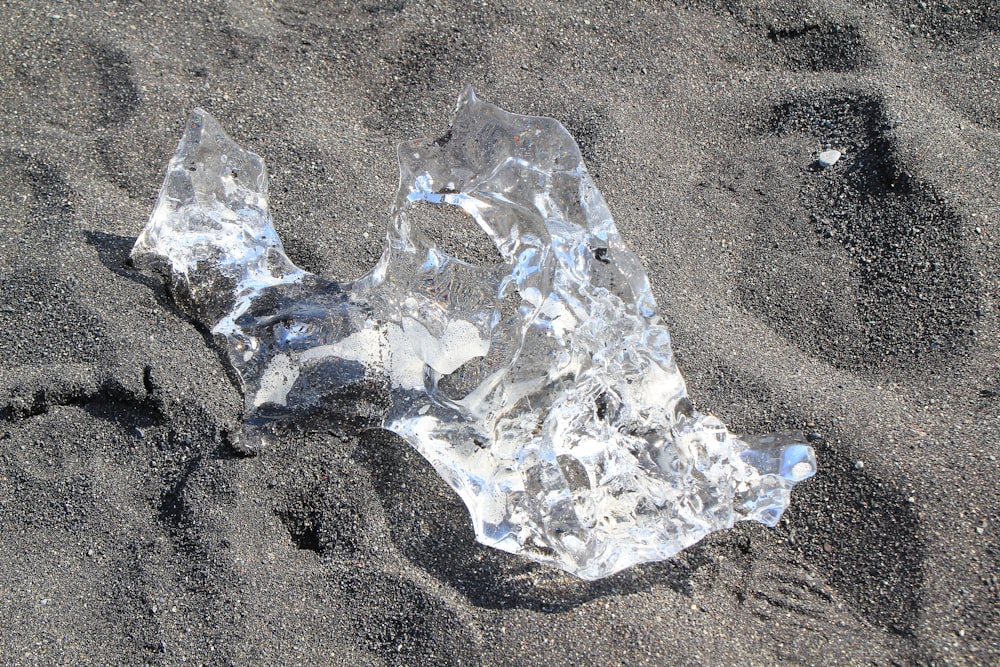 a piece of ice sitting on top of a sandy beach