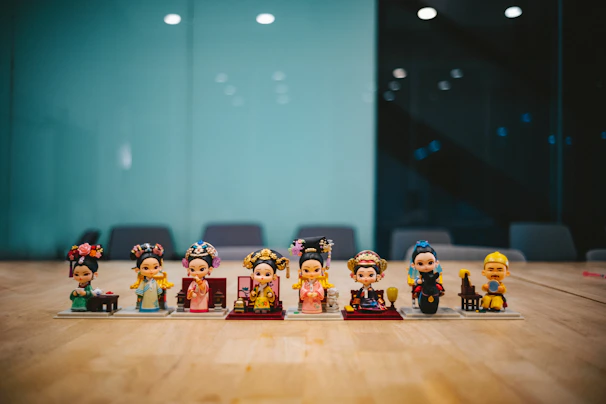 A vibrant display of six detailed Temasek legend figurines arranged on a wooden shelf.
