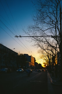 A vibrant city street at dusk with electric vehicles and solar panels visible on buildings.