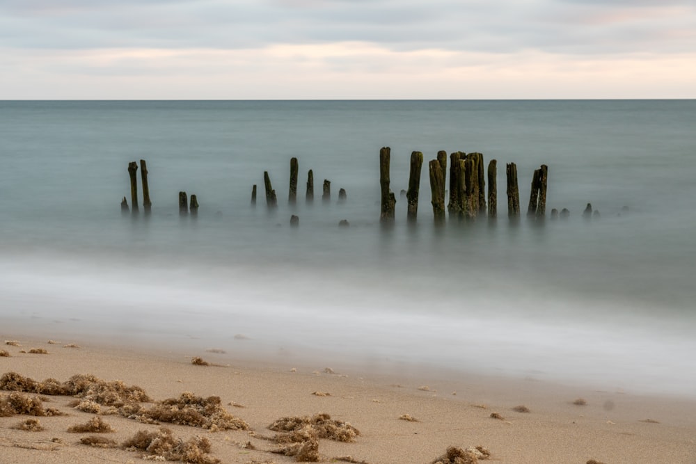 a long exposure photo of a beach with a wooden post sticking out of the water
